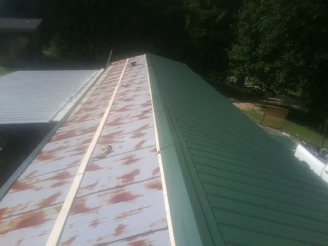 Old rusted panels beside newly installed green metal roofing — Wind Damage Roof Repair by Roofing Brothers in Stevensburg