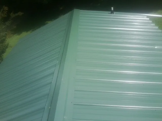 New green metal panels meeting at the ridge of a roof — Flat Roof Repair work by our crew in Stevensburg