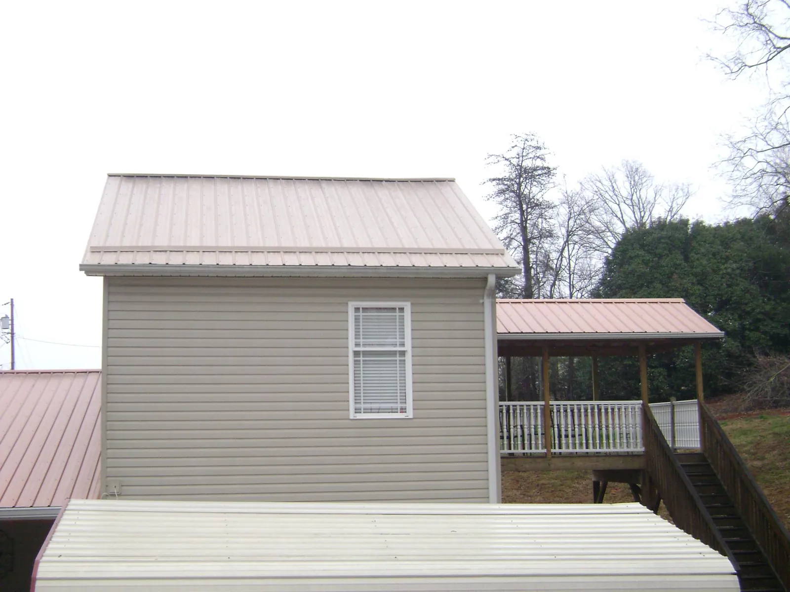 Tan metal roofs on a two story addition and attached porch, from a Roof Replacement job in Stevensburg